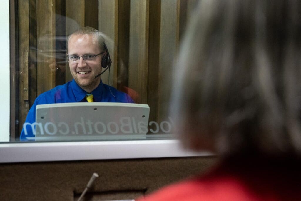 a man smiling inside a hearing test booth