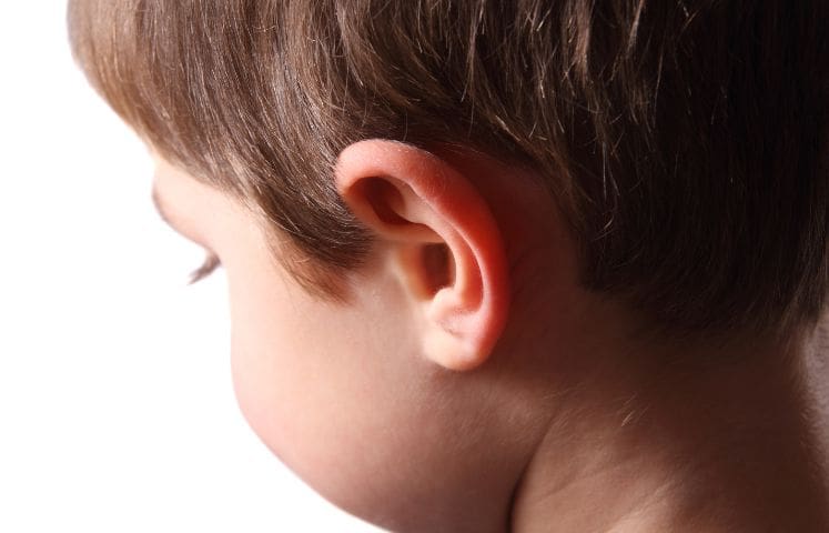 Close-up of a young child’s ear and side of the face, with the child looking down.