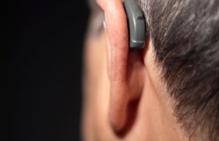 Close-up of a person wearing a behind-the-ear hearing aid.