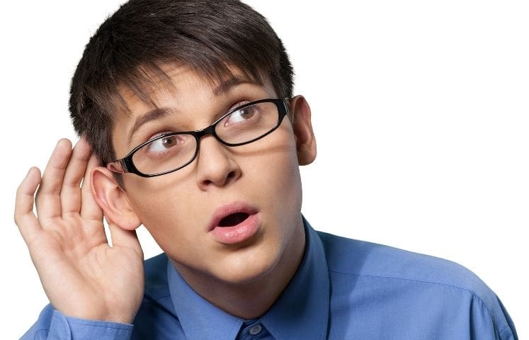 Person wearing glasses holding a hand to their ear with a concerned expression, suggesting early signs of tinnitus or hearing changes.